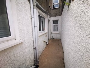 A narrow, enclosed outdoor space with white textured walls, a concrete floor, and a window with a white frame. - 4BR Modern Botanic House (Belfast)