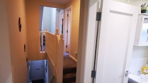 Ein Flur, der zu einem Badezimmer mit Waschbecken und Pflegeartikeln führt.