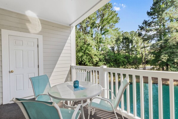 A covered outdoor area with a white door, a round glass table, and four chairs.