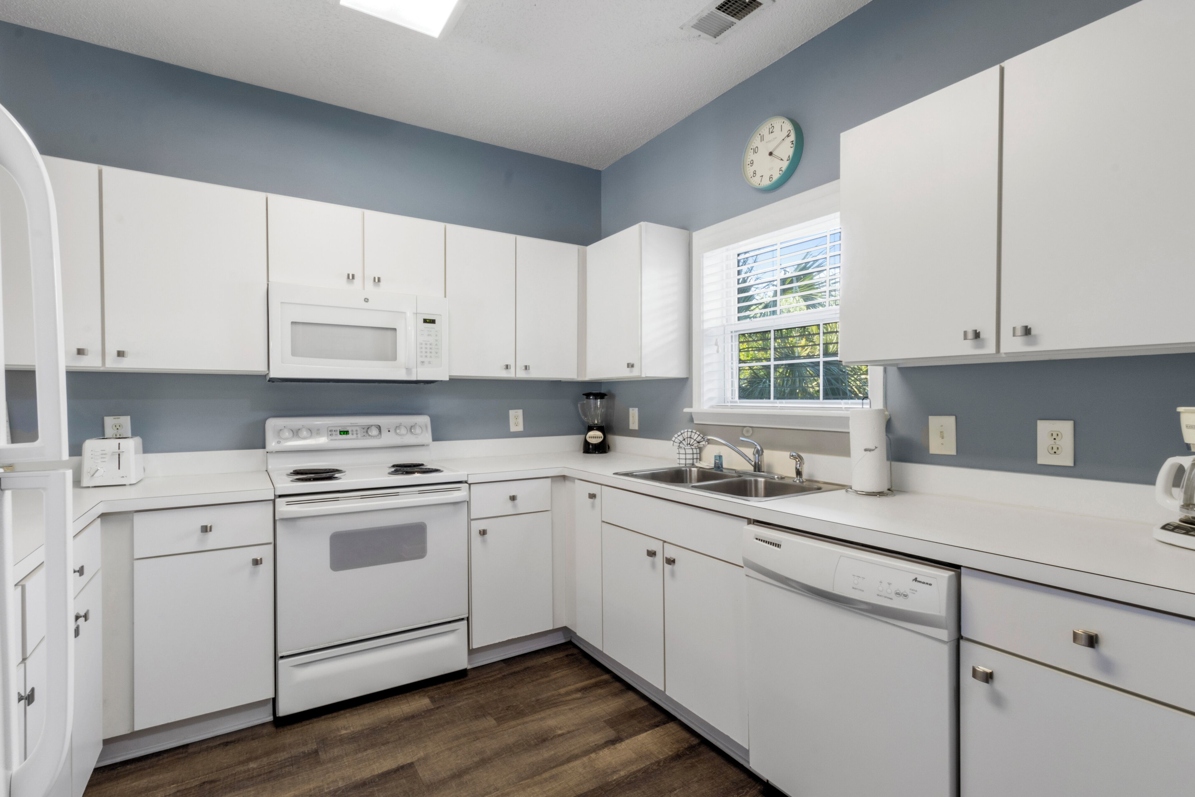 A modern kitchen with white cabinets, a microwave, stove, and dishwasher.