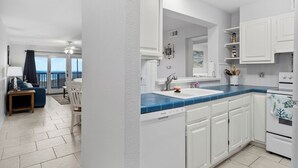 Una cocina moderna con armarios blancos, encimera azul y lavavajillas.