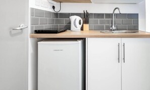 Una cocina equipada con microondas, hervidor y pileta.