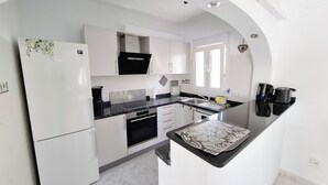 A modern kitchen with white cabinetry, a black countertop, and a built-in oven. - Luxury Villa with Peñon view. 5 Minutes to the beach (Calpe)