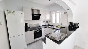 A modern kitchen with white cabinetry, a black countertop, and a built-in oven. - Luxury Villa with Peñon view. 5 Minutes to the beach (Calpe)