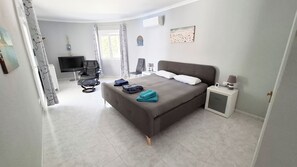 A bedroom with a bed, a chair, a TV, a small table, and a nightstand. - Luxury Villa with Peñon view. 5 Minutes to the beach (Calpe)