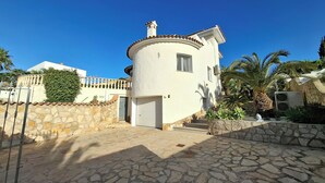 A white building with a circular tower, a stone wall, and a stone-paved entrance. - Luxury Villa with Peñon view. 5 Minutes to the beach (Calpe)