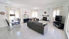 A modern living room with a sofa, TV, fireplace, dining area, and large windows. - Luxury Villa with Peñon view. 5 Minutes to the beach (Calpe)