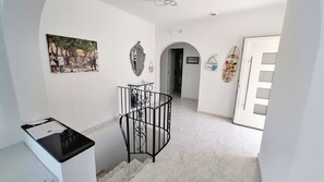 A hallway with a painting, a mirror, a surfboard, and a door. - Luxury Villa with Peñon view. 5 Minutes to the beach (Calpe)
