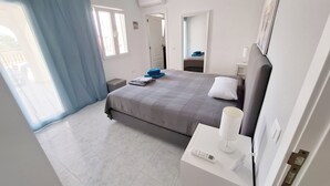 A hotel room with a bed, a bedside table with a lamp, a window with curtains, and a door. - Luxury Villa with Peñon view. 5 Minutes to the beach (Calpe)