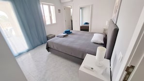 Une chambre d’hôtel avec un lit, une table de chevet avec une lampe, une fenêtre avec des rideaux et une porte.