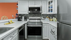 Una cocina moderna con armarios blancos, electrodomésticos de acero inoxidable y salpicadero de azulejos.