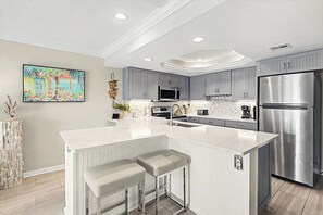 Una cocina moderna con una isla grande, electrodomésticos de acero inoxidable y un backsplash de baldosas en patrón de espiga.