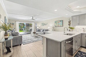 Una cocina moderna con una isla grande, muebles grises y vistas al exterior.