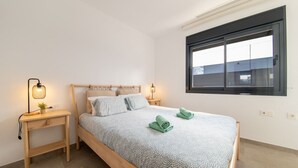 A bedroom with a bed, bedside lamps, a small table, and a window. - Villa Armonia - Heated Pool - Countryside Charm - by OYOOSTAYS (Daya Nueva)