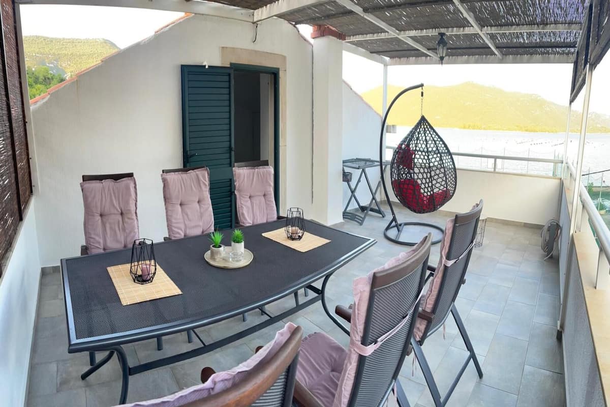 An outdoor dining area with a round table, chairs, and a hanging chair.
