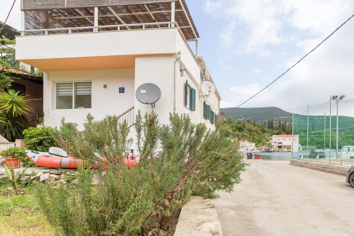 A two-story building with a balcony, satellite dish, and a view of the surrounding landscape.