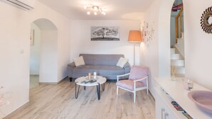 A modern living room with a grey sofa, a round coffee table, a white armchair, and a floor lamp. - Holiday Home Riva (Ston)