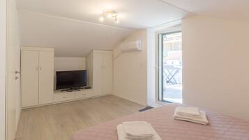 A bedroom with a TV, wardrobe, and a balcony view.