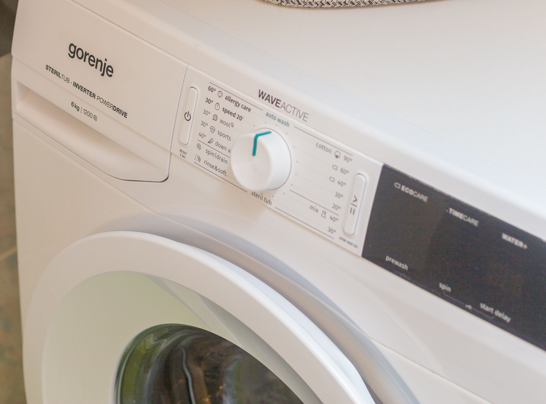 Een witte wasmachine met een bedieningspaneel waarop verschillende instellingen staan, zoals allergieprogramma, snelheid en wasprogramma’s.