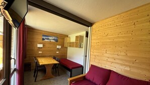 A cozy room with a wooden wall, a wooden table with chairs, a bench, and a red sofa. - 50m from ski lifts, 2nd floor, view ski slopes, balcony, tv, 28m², La Plagne (La Plagne)