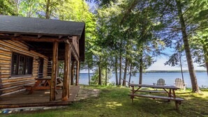 Una cabaña rústica con terraza, con vista a un lago.