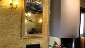 A room with a stone wall, a large mirror, a fireplace, a sofa, and a basket. - La Cour Saint Richer (Basseneville)