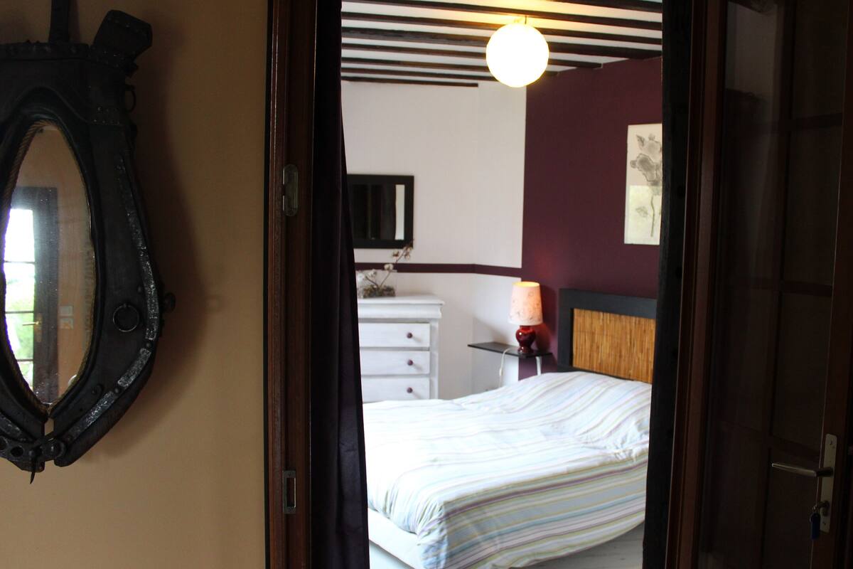 Une chambre à coucher avec un lit, une commode, un miroir et une lampe.