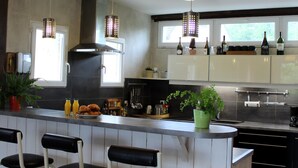A modern kitchen with a central island, bar stools, and a variety of kitchen appliances. - La Cour Saint Richer (Basseneville)