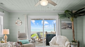 Een kamer met uitzicht op de oceaan, een plafondventilator en een decoratie op het thema strand.