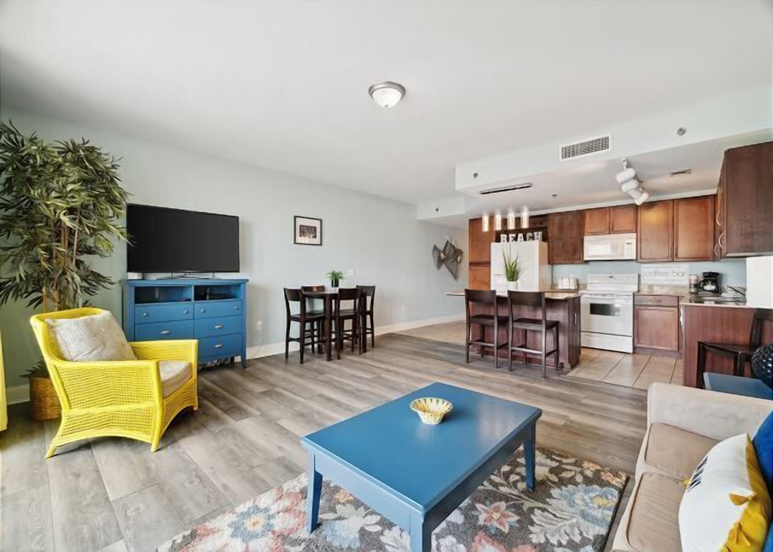 A living room with a blue coffee table, yellow chair, and a TV.