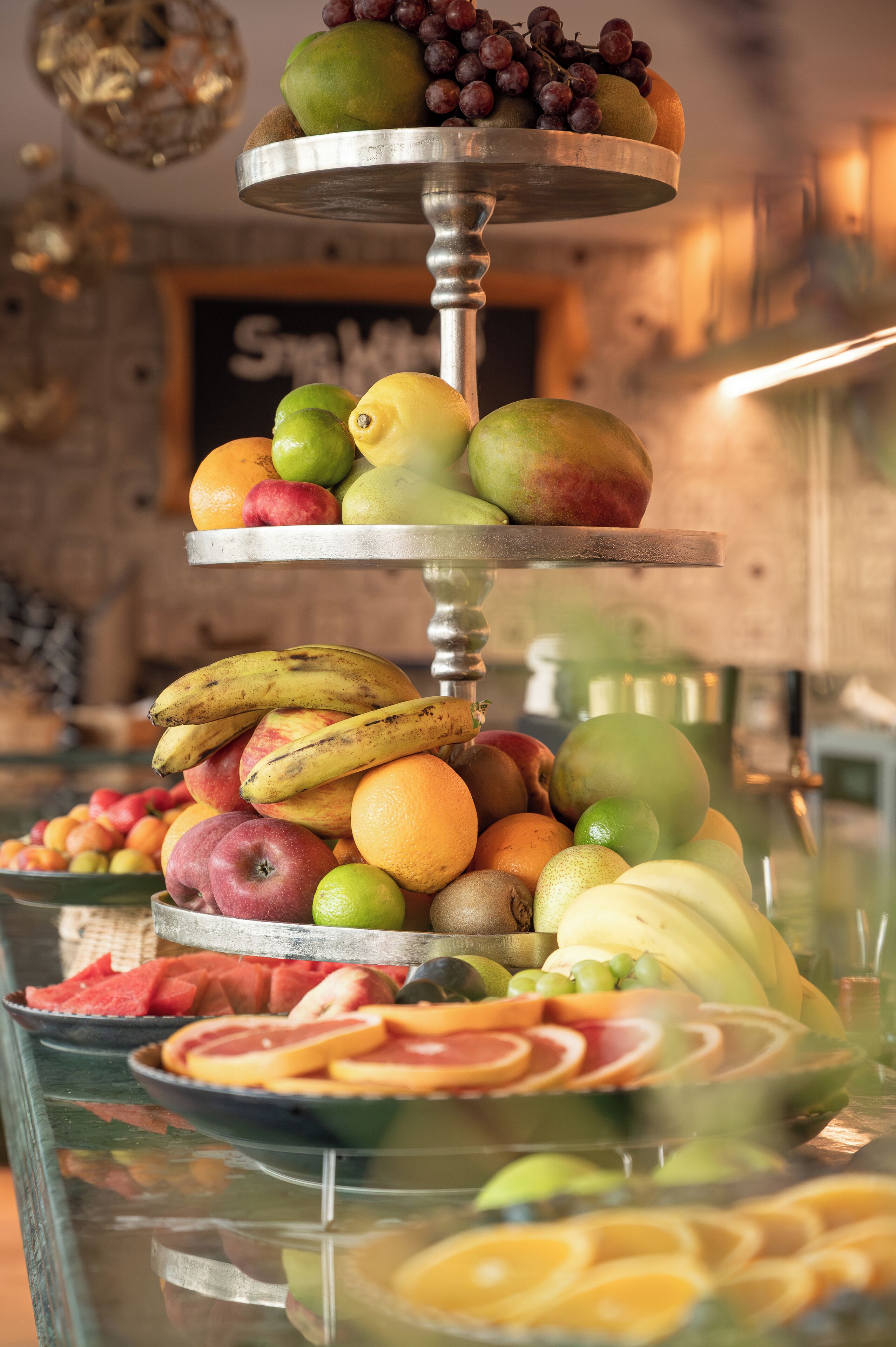 A multi-tiered fruit display with various fruits like apples, bananas, and oranges.