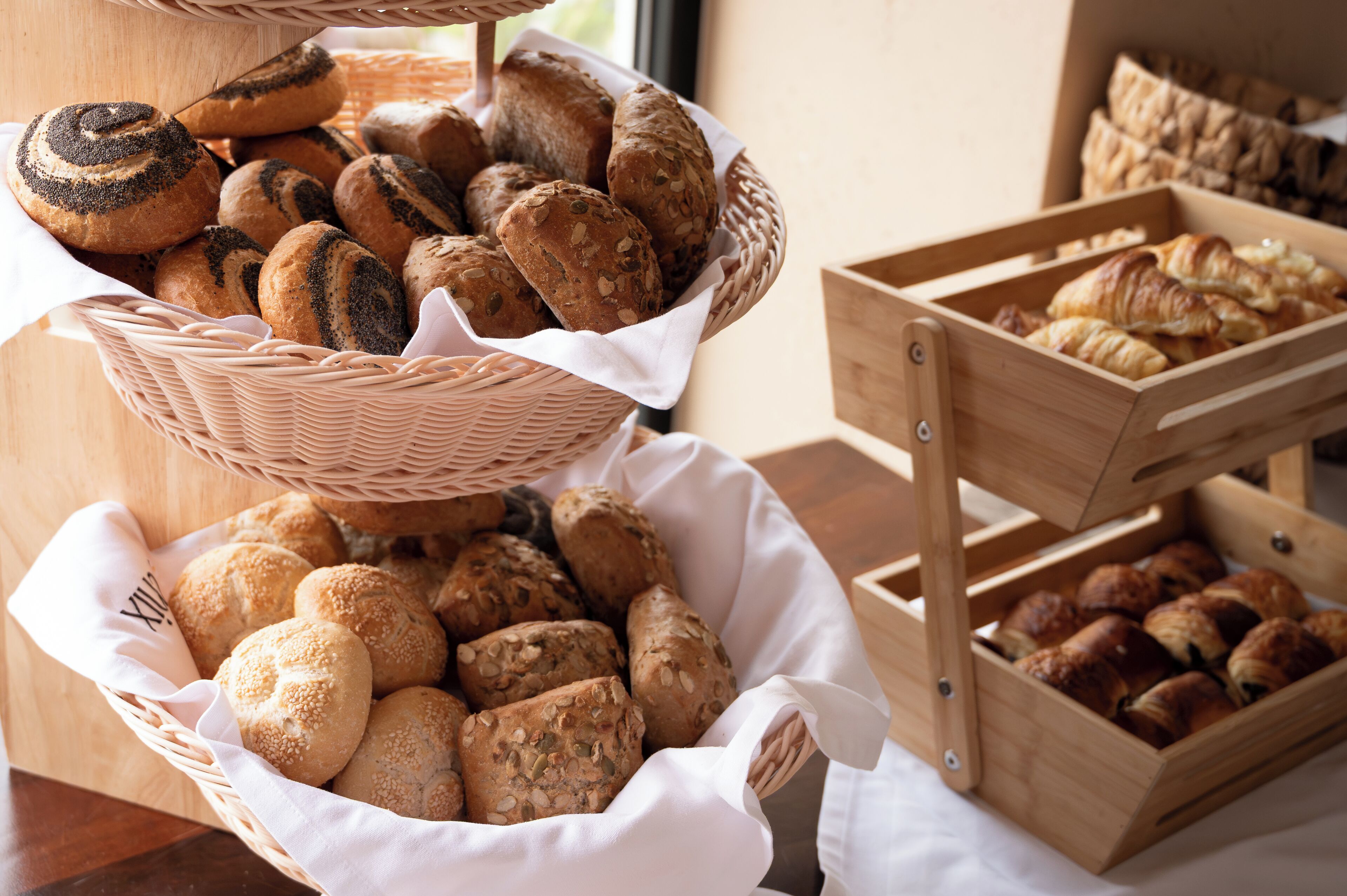 A display of various breads and pastries in wicker baskets and wooden crates.