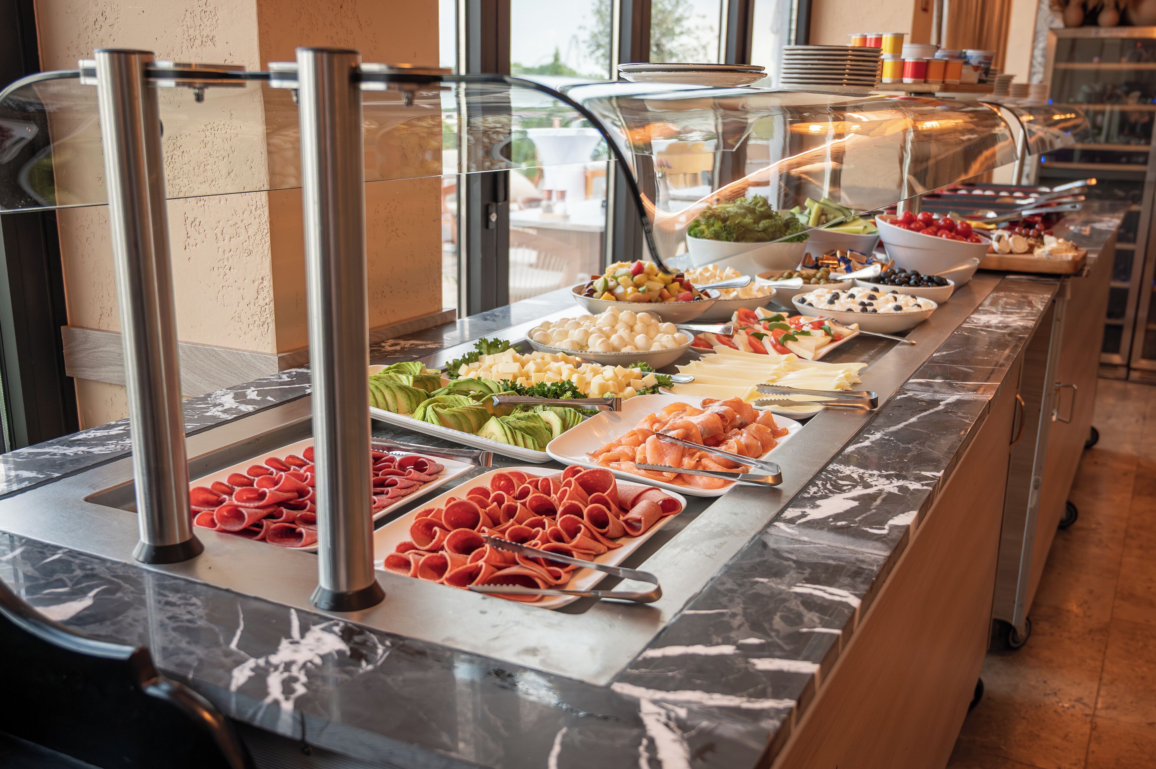 A buffet with various food items including meats, cheeses, and fruits.