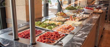 A buffet with various food items including meats, cheeses, and fruits.