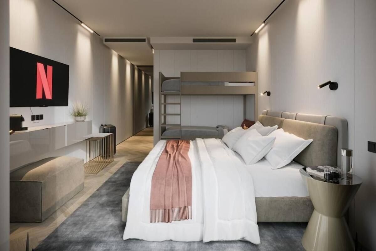 Ein modernes Schlafzimmer mit Etagenbett, Flachbildfernseher an der Wand, Nachttisch und Nachttischlampe.