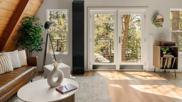 A spacious loft with a high ceiling, large windows, a cozy seating area, and a fireplace.