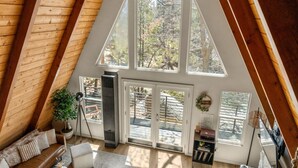 A high-ceilinged room with large windows, a fireplace, and a cozy seating area.