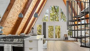A modern kitchen with a large island, wooden beams, and a view of the outdoors.