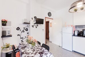 A compact kitchen with a refrigerator, microwave, and toaster. A dining area with a table and chairs is adjacent to the kitchen.