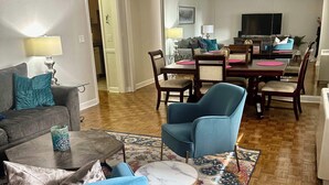 A living room with a sofa, two armchairs, a coffee table, and a dining area with a table and chairs. - FIFA 2026 Walk to Stadium | 2BR Unit 10G ATL (Atlanta)