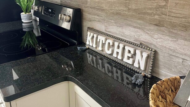 A kitchen with a black countertop, stainless steel appliances, and a wooden backsplash. - FIFA 2026 Walk to Stadium | 2BR Unit 10G ATL (Atlanta)