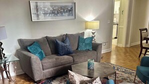 A living room with a grey sofa, blue armchair, and a coffee table. - FIFA 2026 Walk to Stadium | 2BR Unit 10G ATL (Atlanta)