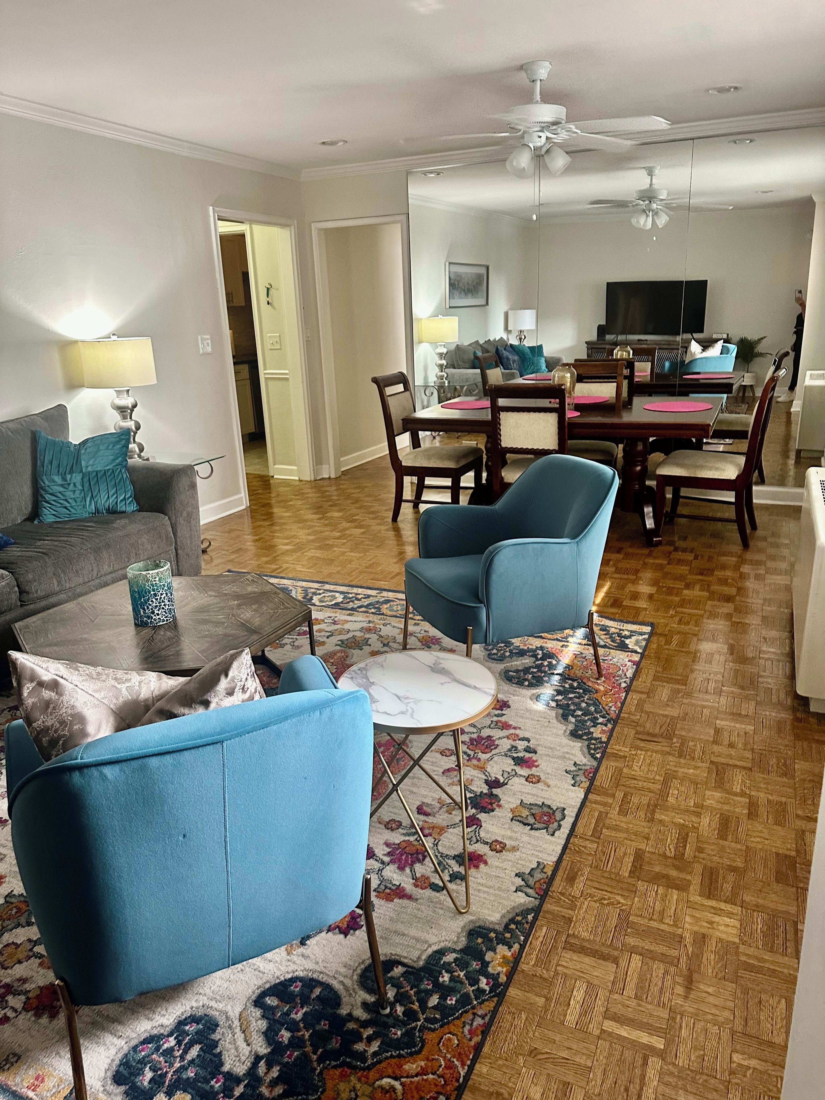 A living room with a sofa, armchairs, a coffee table, and a dining area with chairs and a table.