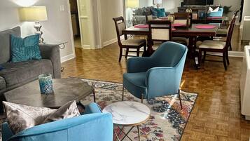 A living room with a sofa, armchairs, a coffee table, and a dining area with chairs and a table.