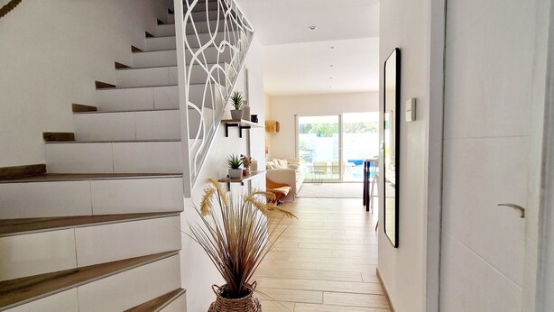 A modern interior with a staircase, a potted plant, and a hallway leading to a room with a large window. - 3 bedroom private vacation home in agde (Agde)