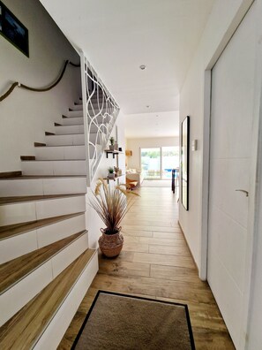 A modern interior with a staircase, a potted plant, and a hallway leading to a room with a large window. - Private 3-Bedroom Vacation Home in Agde (Agde)