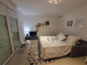 Relax in a spacious bedroom with a large bed, television, and small table with a lamp.