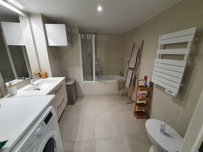 Enjoy a convenient bathroom with a central sink, washing machine, shower enclosure, and toilet.