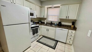 A compact kitchen with white cabinets, a white refrigerator, a microwave, a stove, and a sink. - Steps From UNMC, Dining, Explore Midtown (Omaha)