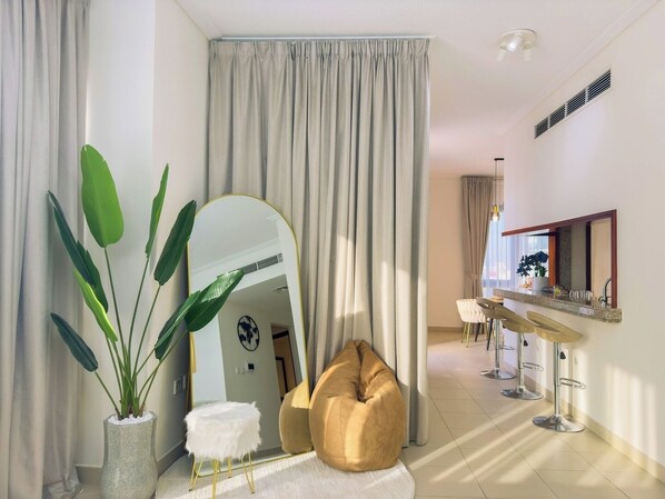 A modern room with a large mirror, a beige bean bag, a white furry stool, and a plant in a textured vase.